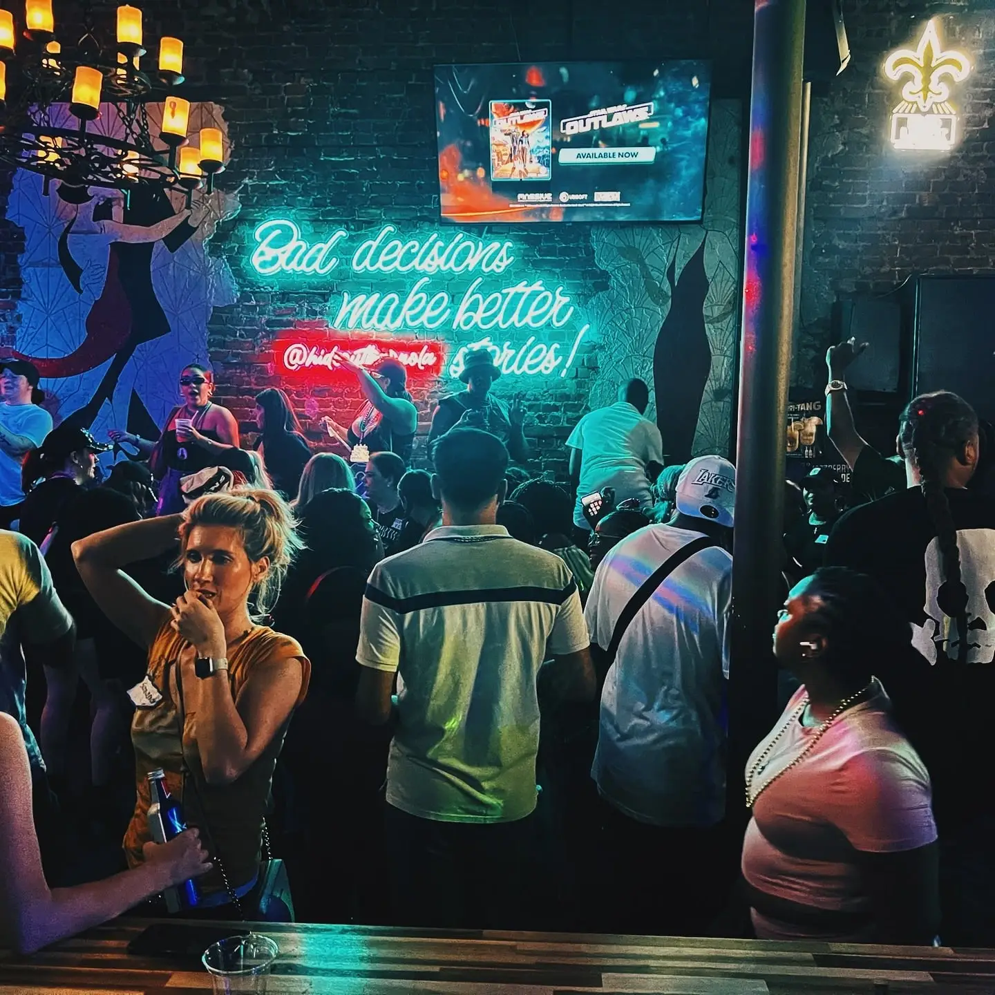 A packed crowd in front of the stage and the “Bad decisions make better stories!” neon sign